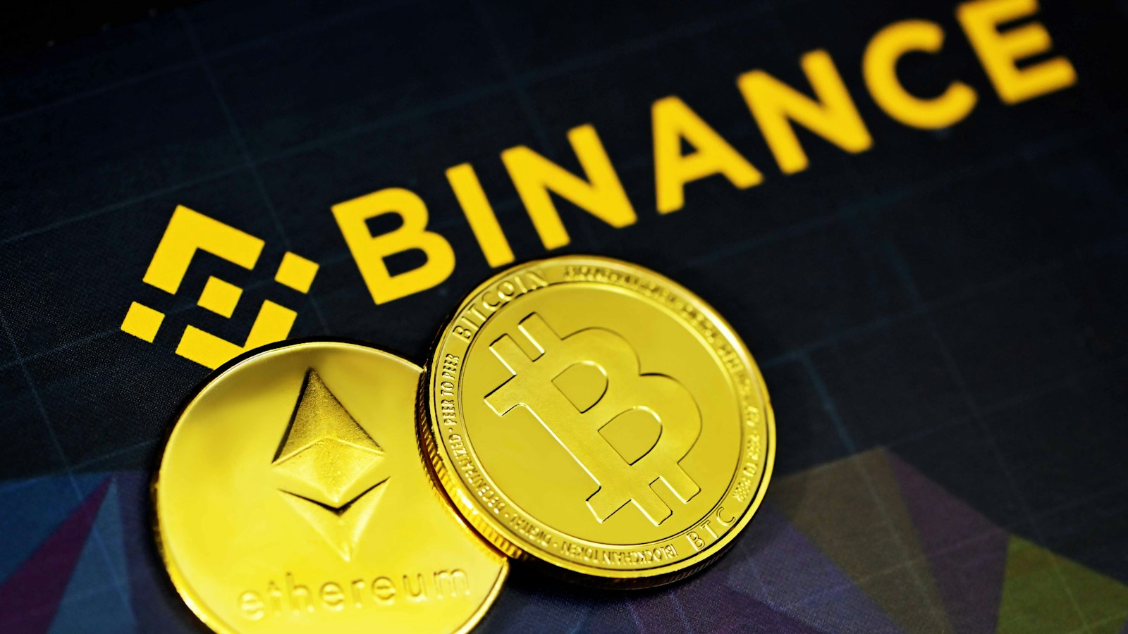 Physical Bitcoin and Ethereum tokens beside a Binance sign, an archival illustrative photograph published in July 2021, not a photograph of the suspected breach.