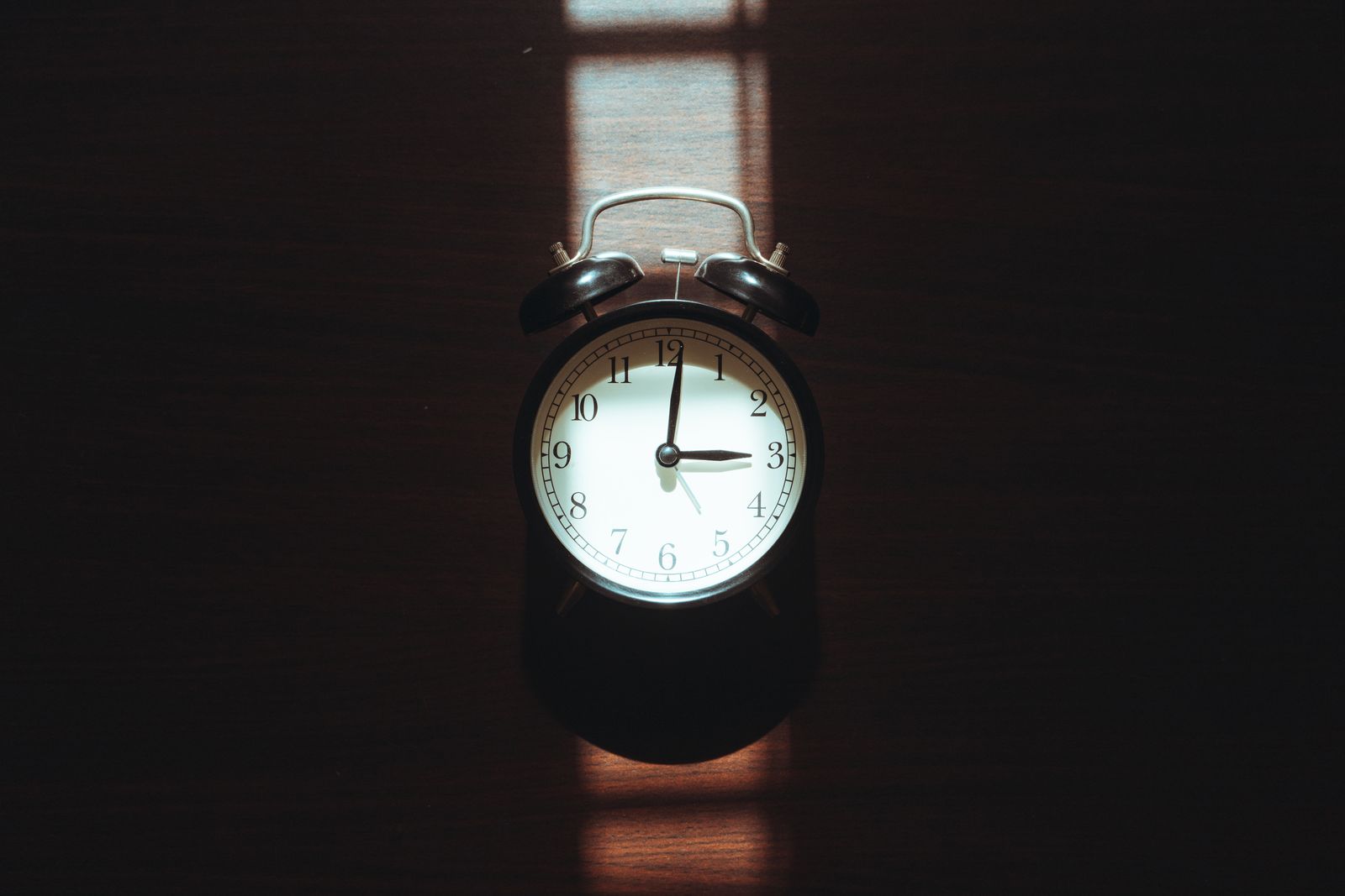 A vintage analogue alarm clock in a shaft of sunlight; illustrative stock photograph, not a depiction of the 2am changeover.