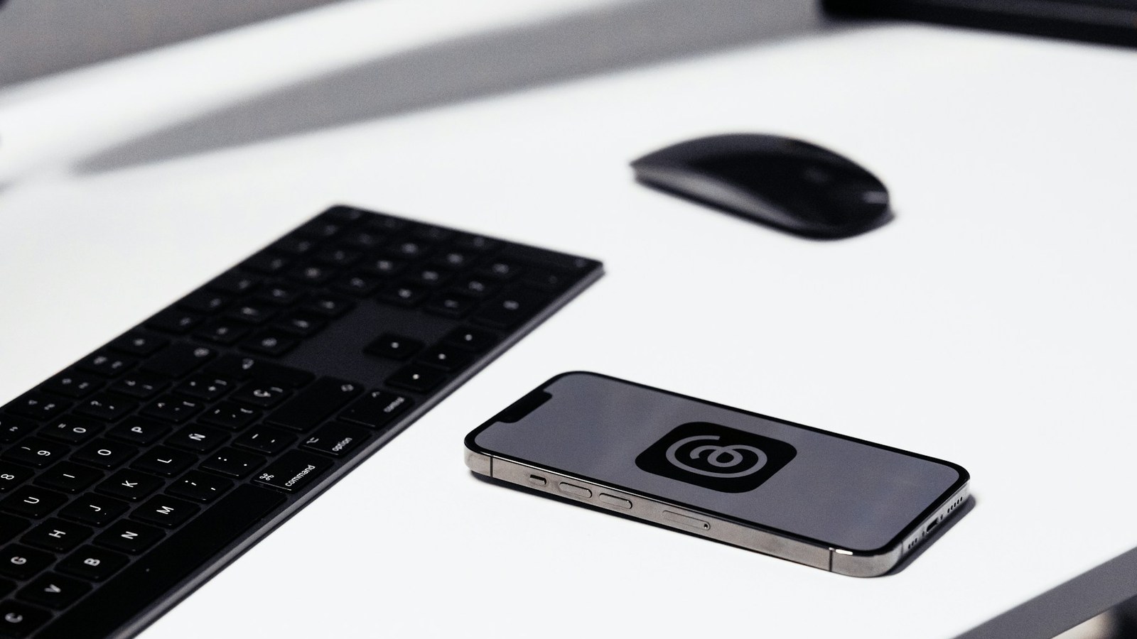 Real smartphone running Meta's Threads app beside a keyboard and mouse.
