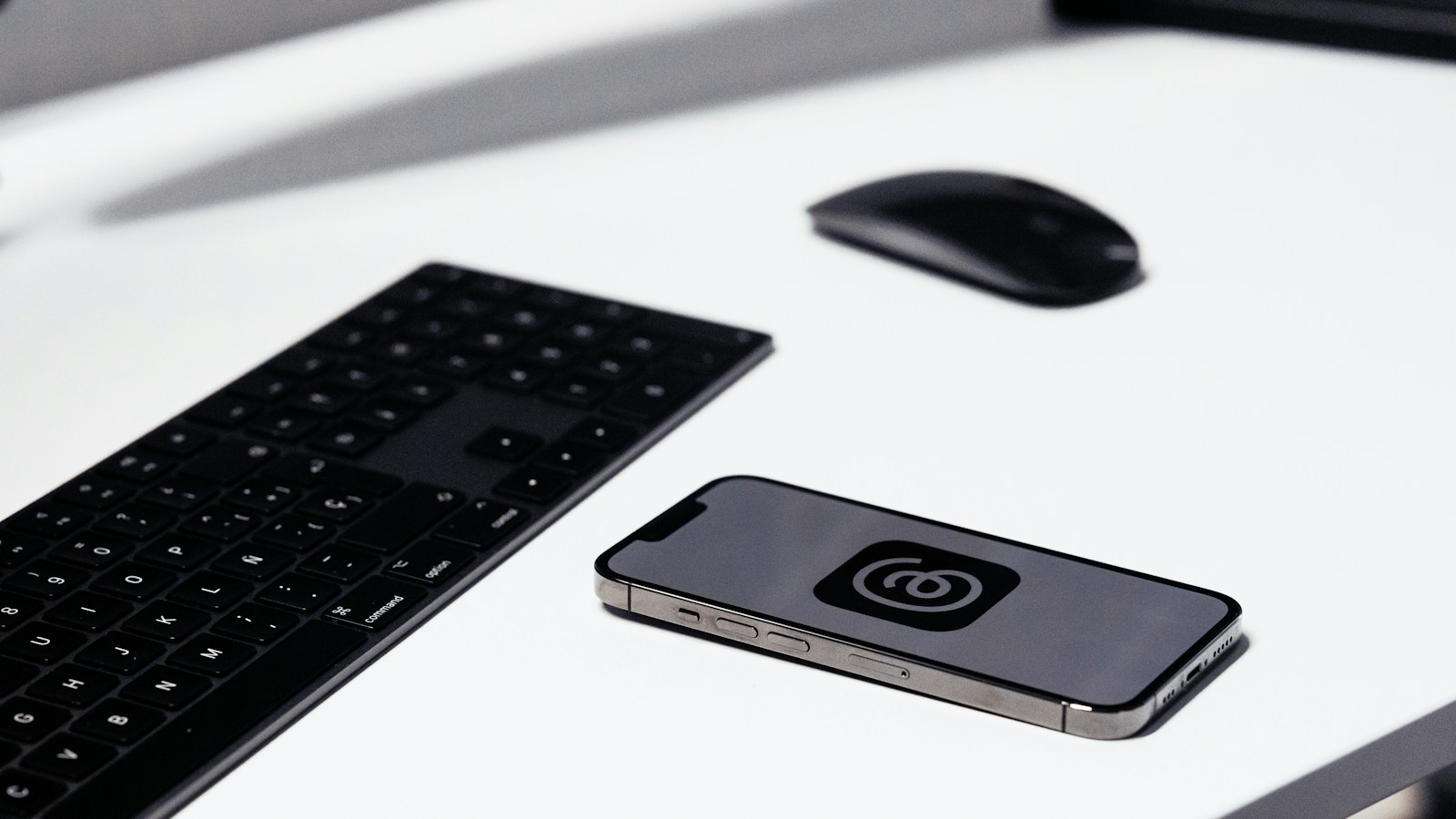 Smartphone displaying Meta's Threads app beside a keyboard and mouse, photographed in 2023.